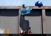 A Central American migrant hands over a container of water as he disembark from a freight train